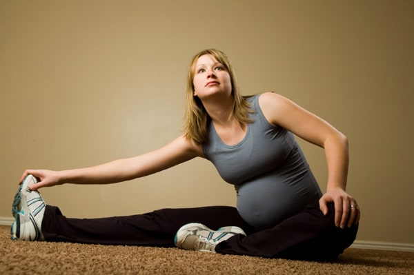 Pregnant lady doing stretches on the floor