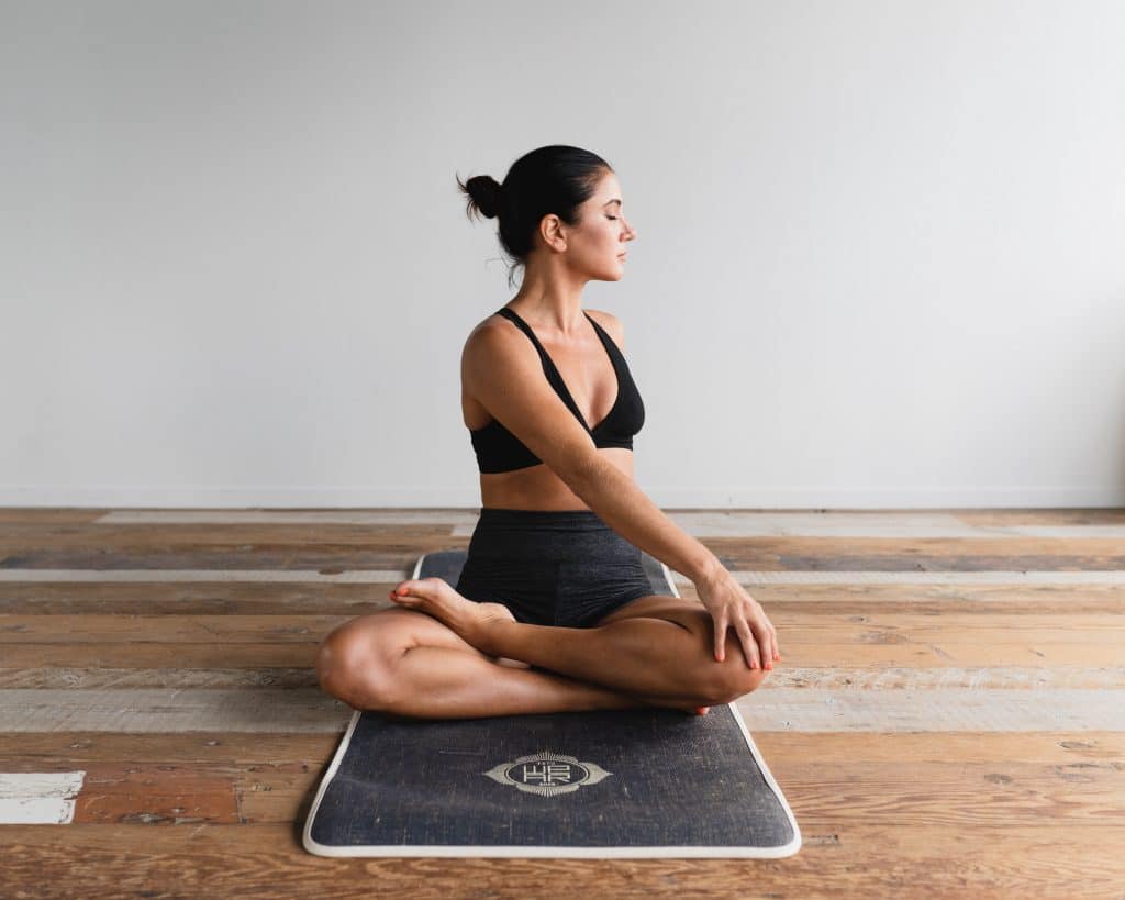 woman stretching cross legged on yoga mat